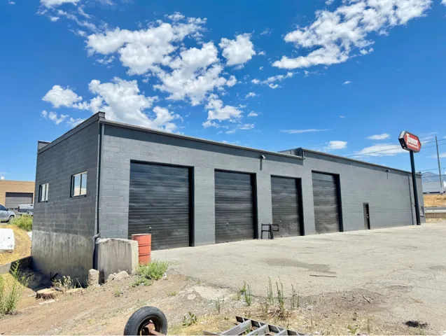 Commercial building with a flat roofline, grey block construction, and multiple black roll-up doors