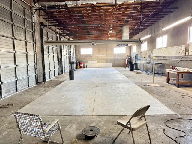 Concrete flooring with an open beam ceiling and multiple large roll-up doors