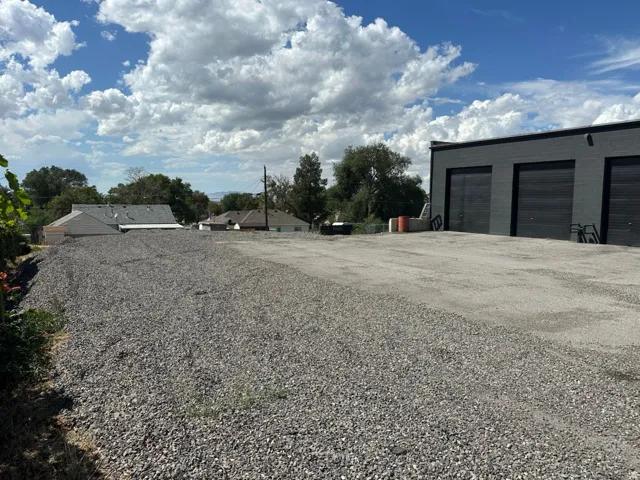 Gravel lot featuring an adjacent building with three roll-up doors