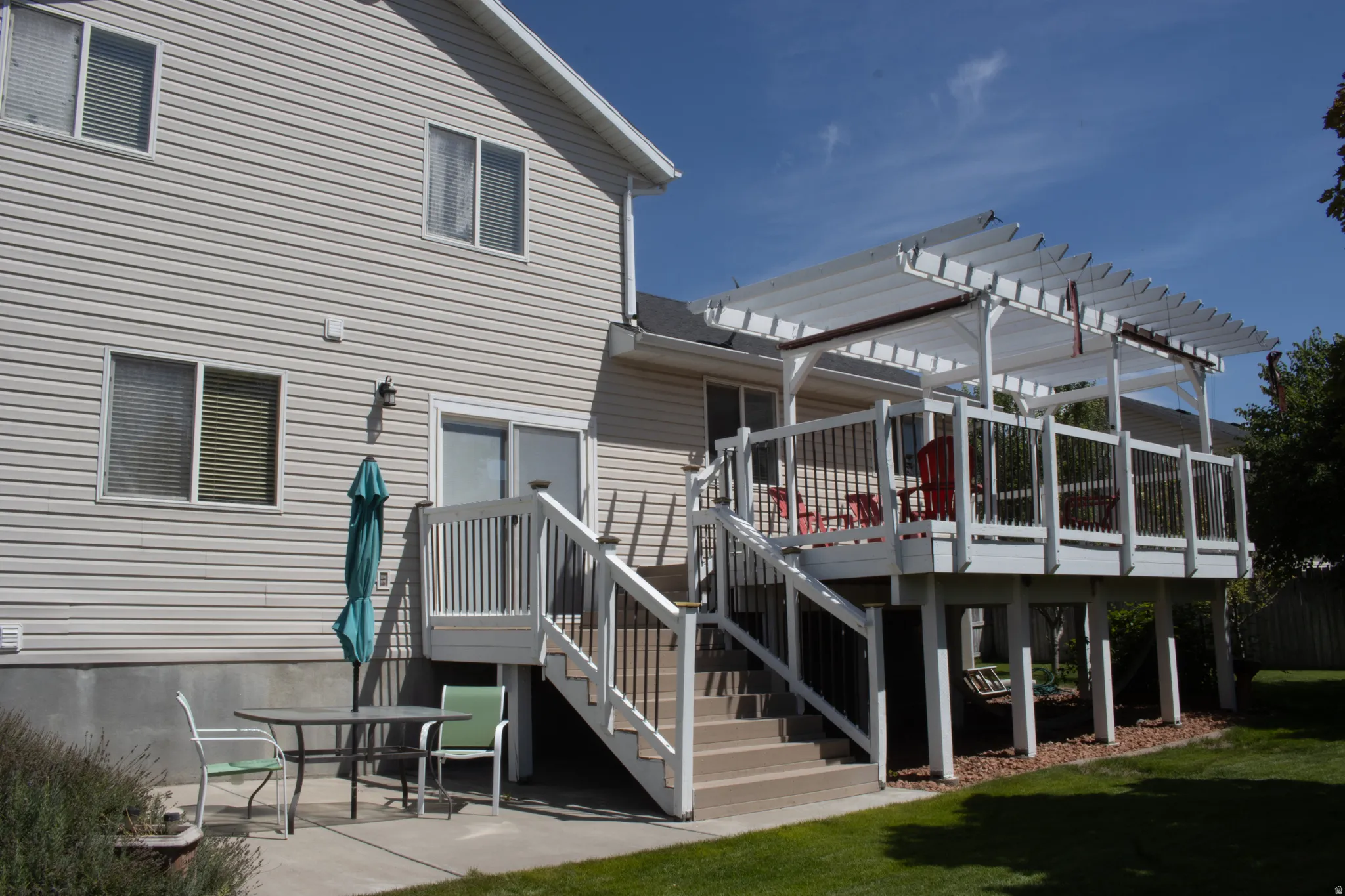 Expansive outdoor deck with white railing, integrated pergola, and a private staircase