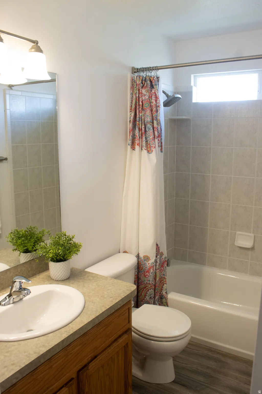 Bathroom featuring a single vanity with wood-finish cabinetry, a drop-in sink, and a light-toned countertop