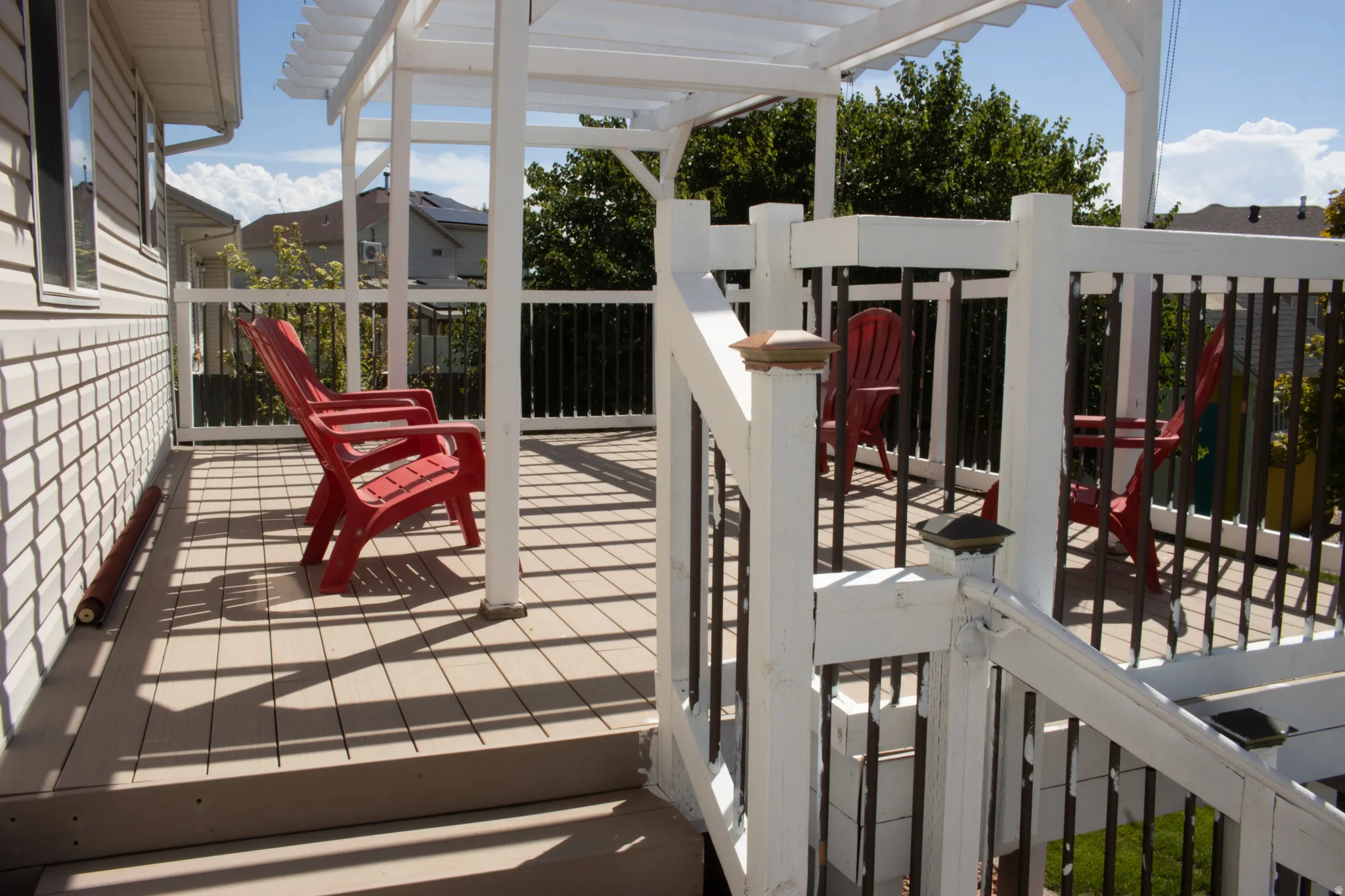 Expansive outdoor deck featuring a white pergola, composite decking, and matching white railings with dark balusters