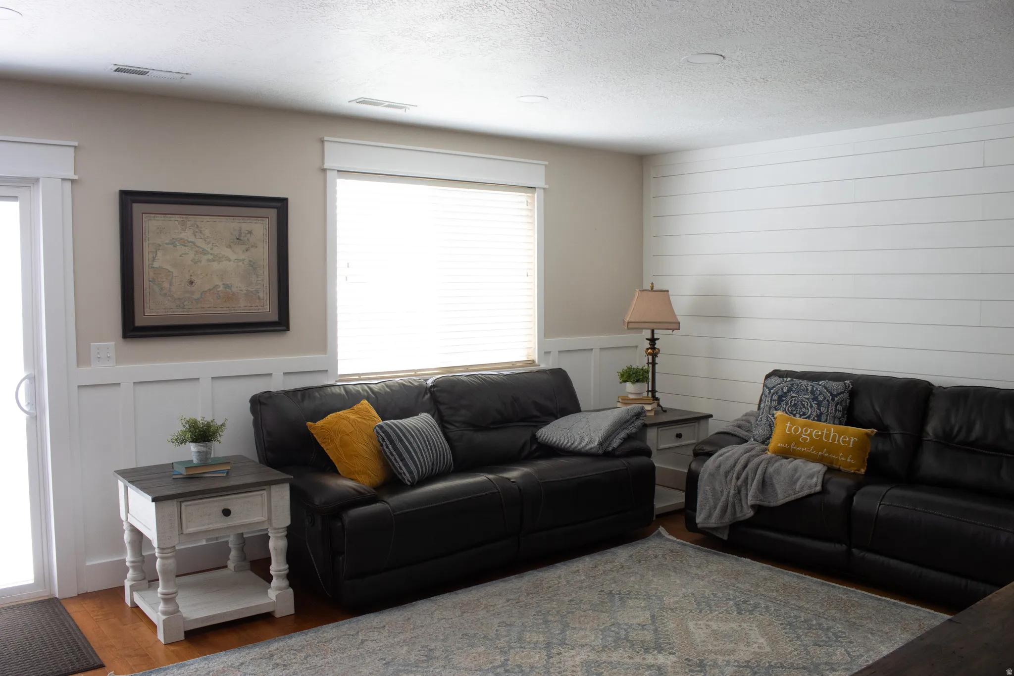 White shiplap accent wall, white wainscoting, wood-finish flooring, and white window blinds