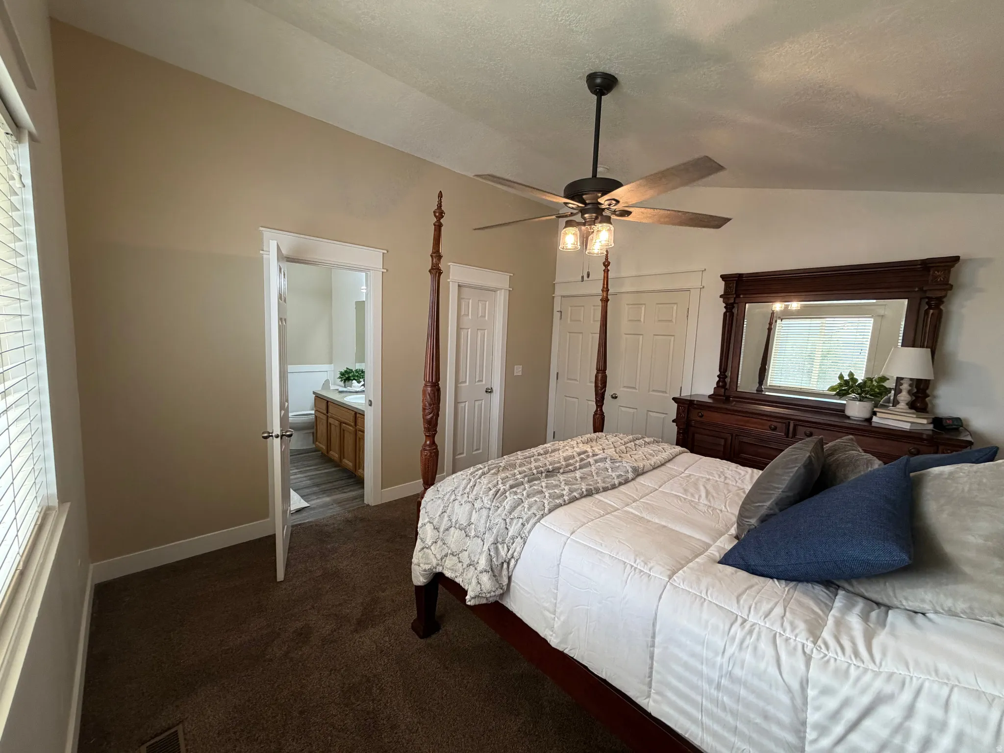 Vaulted ceiling, ceiling fan with integrated lighting, wood-finish flooring in bathroom, bathroom vanity with integrated sink, interior door with white trim