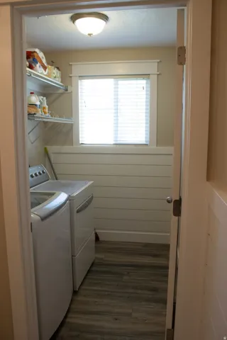 Wood-finish flooring, white shiplap wall accent, window with white blinds, flush mount ceiling light, and built-in wire shelving