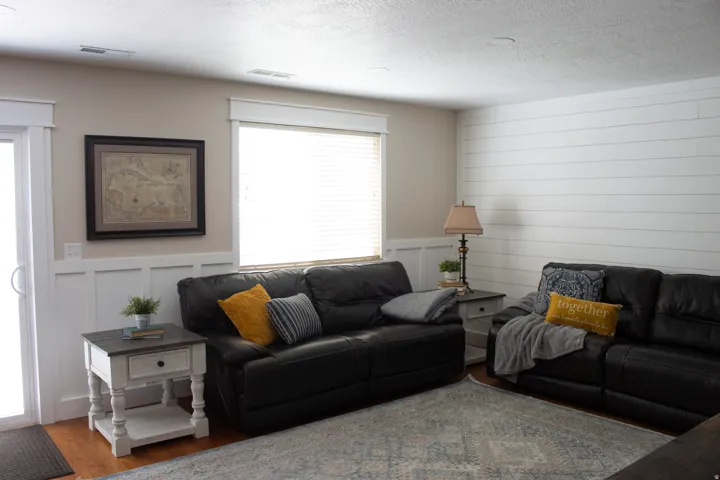 White shiplap accent wall, white wainscoting, wood-finish flooring, and white window blinds