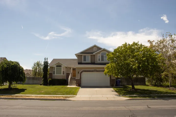 Two-story residence featuring a front-facing garage, bay window, and a light-colored exterior with darker trim