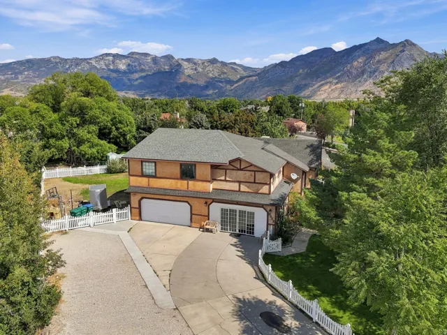 Tudor Revival-style residence with a two-car garage, mature trees, and a mountain backdrop