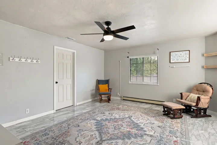 Recessed window with blinds, ceiling fan with integrated lighting, door with panel detailing, and wood-finish flooring
