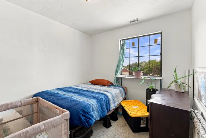 Square-gridded window with a built-in shelf, textured white walls, and a ceiling-mounted light fixture