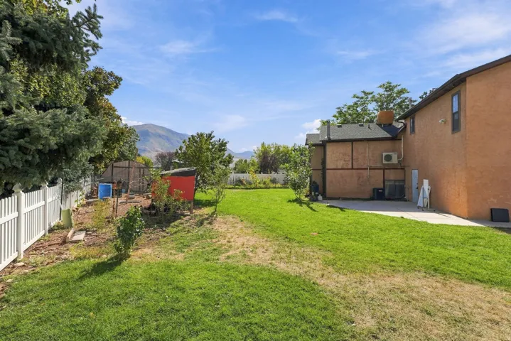 Expansive backyard featuring a lush lawn, white picket fencing, and a concrete patio