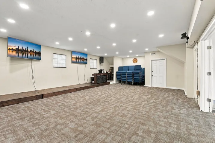 Spacious room with recessed lighting, patterned carpet flooring, and a raised stage area