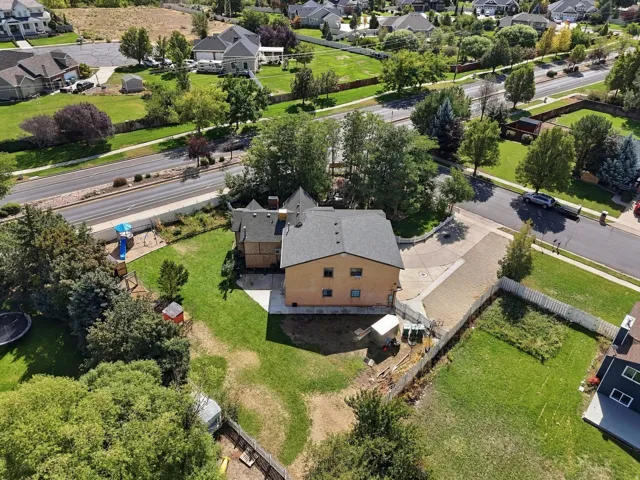 Expansive lot with mature trees, paved driveways, a large grassy area, and perimeter fencing