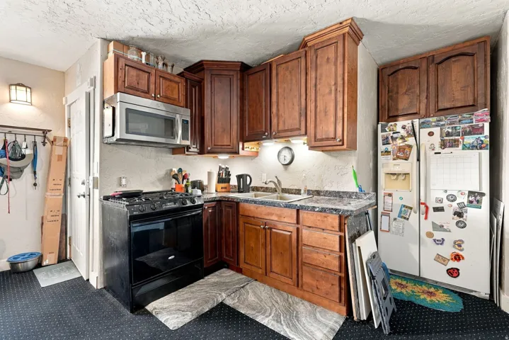 Corner kitchen layout featuring wood-finish cabinetry, a stainless steel over-the-range microwave, and a gas range