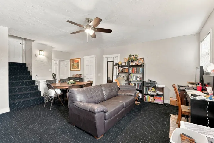 Carpeted flooring throughout, with a ceiling fan featuring integrated lighting