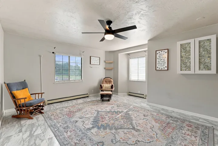 Recessed windows with blinds, ceiling fan with integrated lighting, wall-mounted cabinetry, and built-in shelving