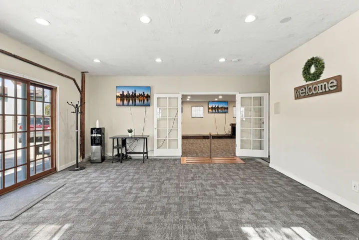 Spacious room featuring patterned carpet flooring, recessed lighting, and a sliding glass door