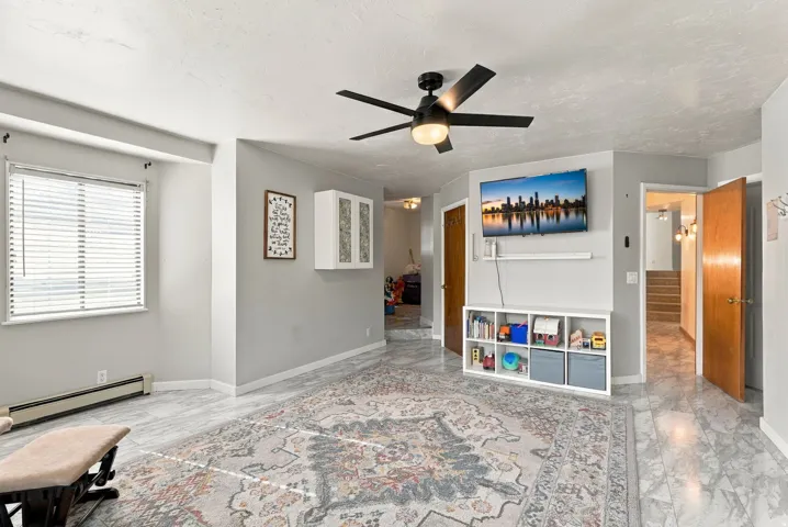 Recessed window with blinds, ceiling fan with integrated lighting, built-in wall cabinetry, light-toned wall finishes, and wood-finish flooring