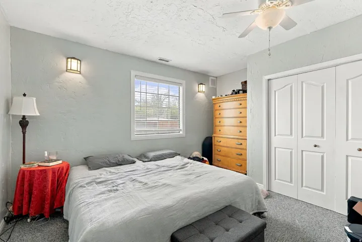 Recessed window with blinds, ceiling fan, bi-fold closet doors, and wall-mounted sconce lighting