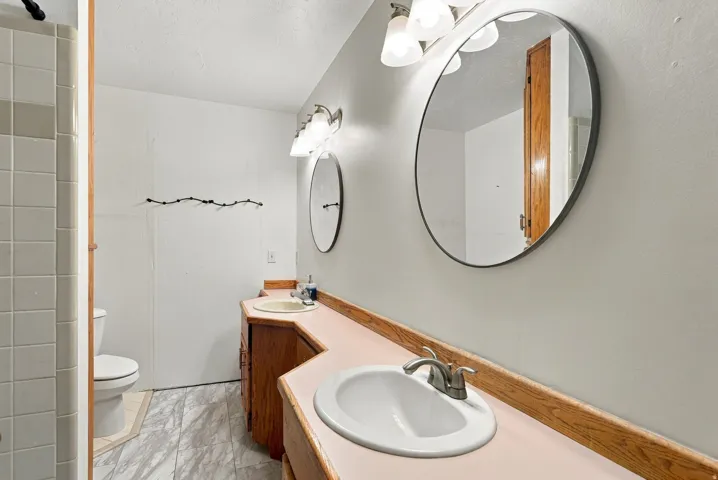 Dual vanity with integrated sinks, brushed nickel faucets, and wood-finish cabinetry