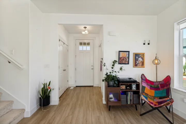 Entry foyer with wood-finish flooring, white paneled door with glass inserts, and an overhead light fixture