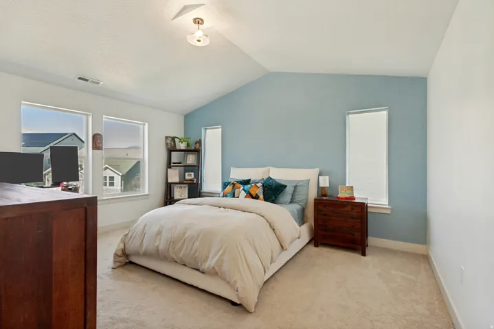 Vaulted ceiling, two large windows, two narrow windows, carpet flooring, and a flush mount light fixture
