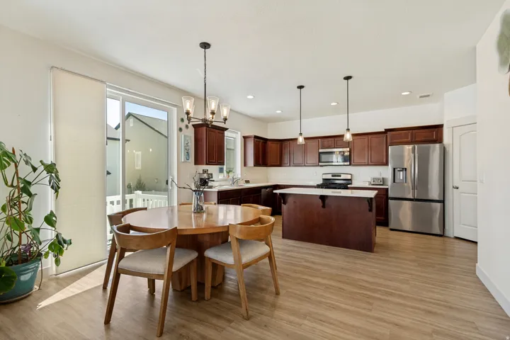 Wood-finish flooring throughout, dark wood cabinetry, white countertops, stainless steel appliances, and a sliding glass door