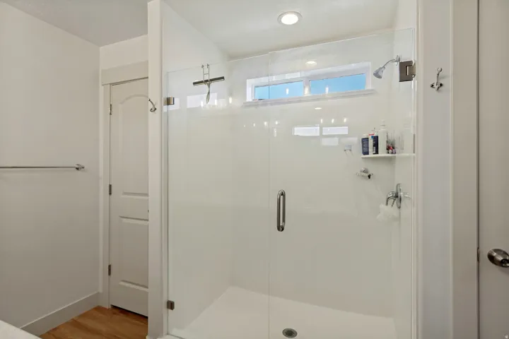 Glass-enclosed shower with a fixed showerhead and built-in shelving