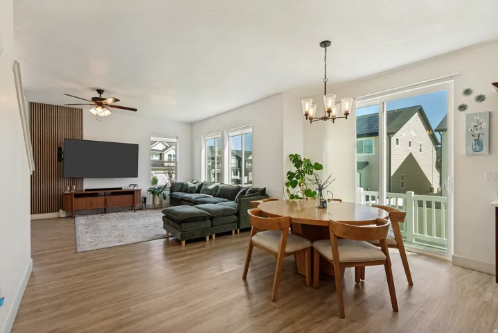 Open-concept living space featuring wood-finish flooring, multiple windows, and a sliding glass door