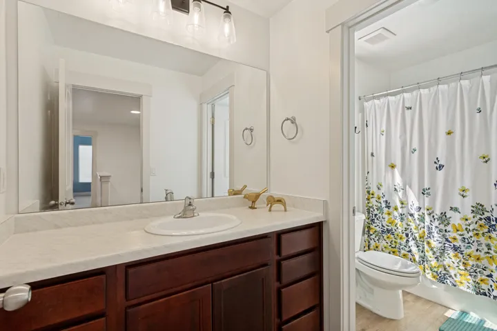 White vanity with an integrated sink, broad mirror, and contemporary light fixture
