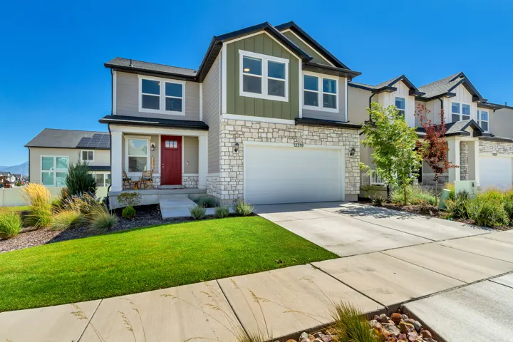 Two-story residence featuring a red entry door, an attached two-car garage, and a concrete driveway