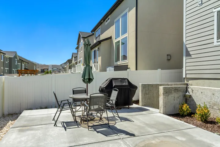 Private concrete patio with a white vinyl fence and concrete retaining walls