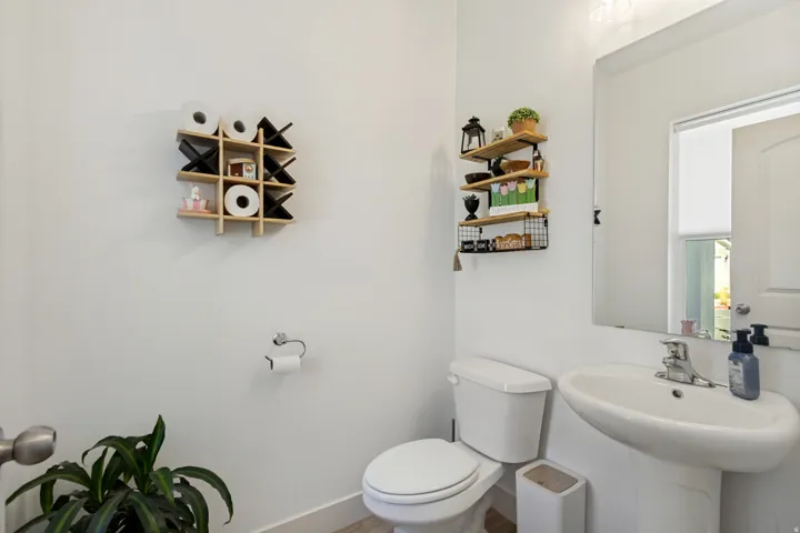 Pedestal sink with chrome faucet, wall-mounted mirror, and white toilet