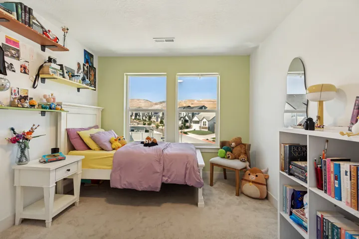 Dual windows providing ample natural light, painted accent wall, wall-mounted shelving, built-in shelving unit, and carpeted flooring