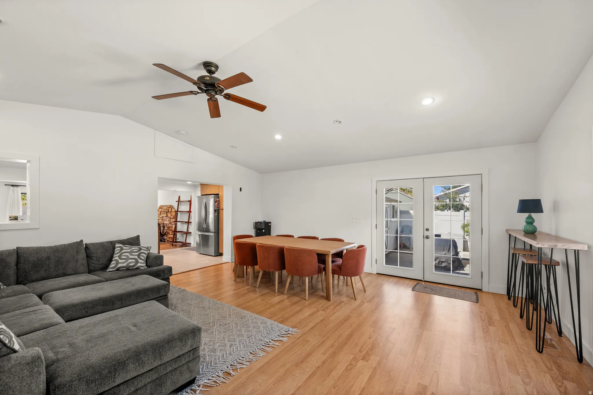 Vaulted ceilings, wood-finish flooring, recessed lighting, and a ceiling fan