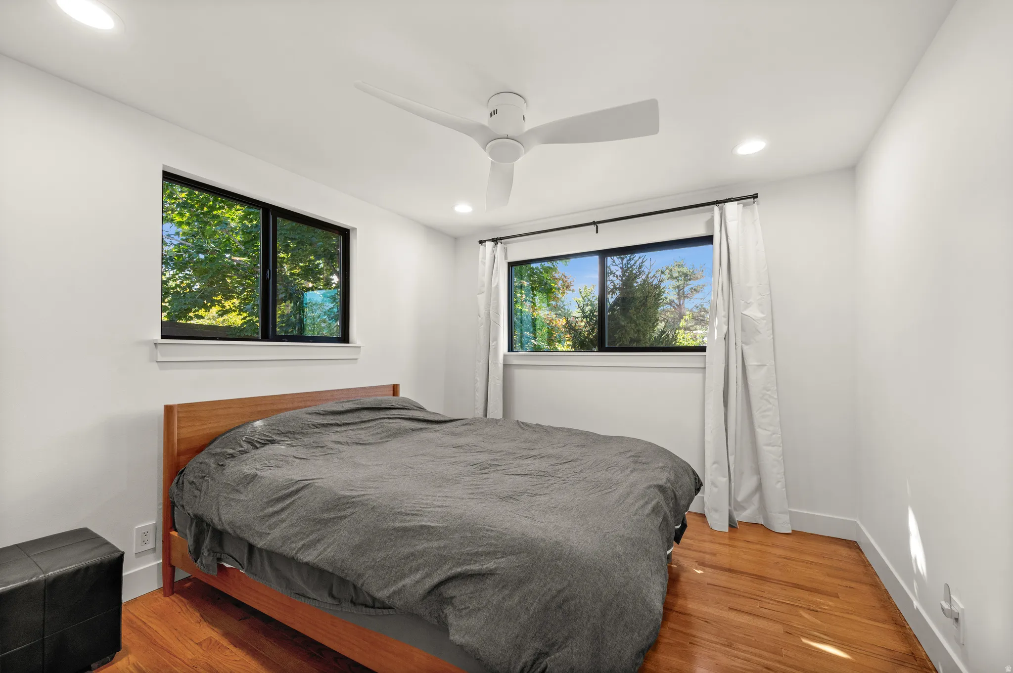 Recessed ceiling lighting, wood-finish flooring, white walls, and a ceiling fan with integrated lighting