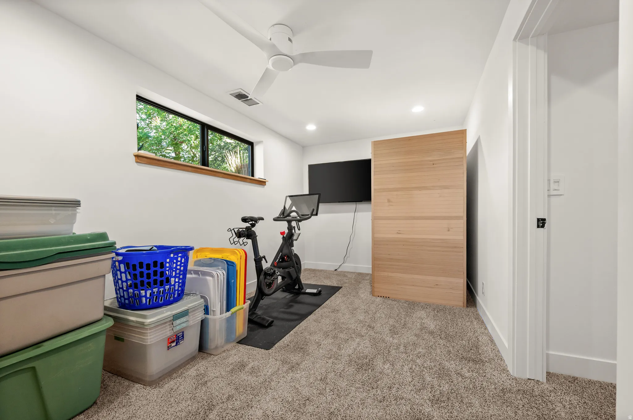 Carpeted room with a horizontal window, white walls, and a ceiling fan