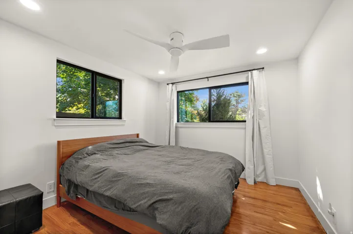 Recessed ceiling lighting, wood-finish flooring, white walls, and a ceiling fan with integrated lighting