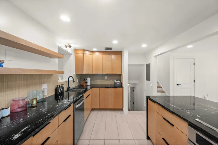 Kitchen featuring wood cabinetry, black countertops, tile flooring, and recessed lighting