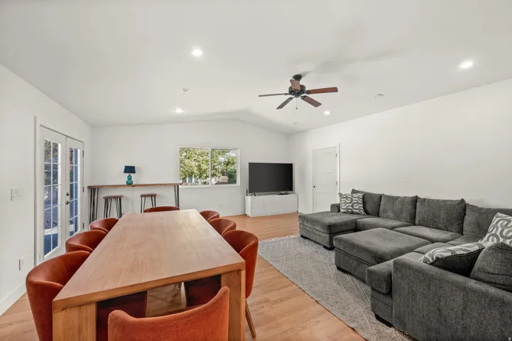 Vaulted ceiling with recessed lighting, wood-finish flooring, white walls, and a ceiling fan