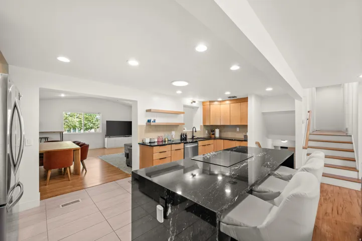 Expansive kitchen island with dark stone countertop, built-in cooktop, and recessed lighting