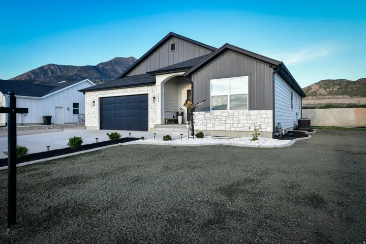 Contemporary exterior with a dark gray garage door, light stone façade, and contrasting vertical and horizontal siding