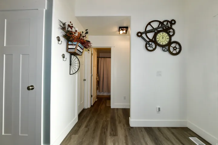 Wood-finish flooring throughout, white interior doors, and recessed lighting in the hallway