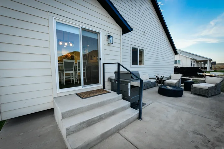 Exterior featuring horizontal siding, a sliding glass door, and a multi-level concrete patio with a black metal railing