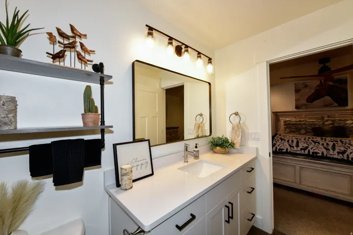 White vanity with a rectangular undermount sink, a chrome faucet, and black hardware