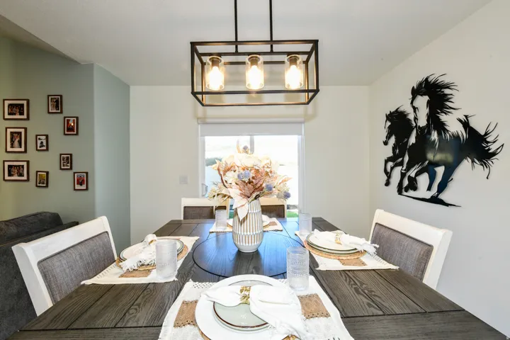 Dining area featuring a rectangular wood-finish table with a contrasting inlay and a linear metal chandelier with exposed bulbs