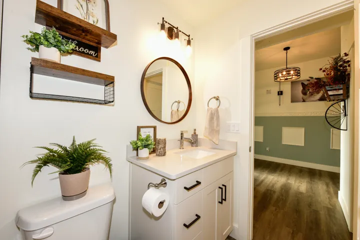 White vanity with a single basin, stainless steel faucet, and dark hardware