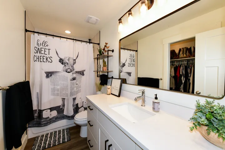 Single vanity with an integrated sink, polished chrome faucet, and expansive wall-mounted mirror