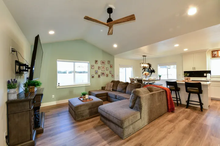 Vaulted ceiling with a wood-finish ceiling fan, wood-finish flooring, recessed lighting, and a built-in fireplace