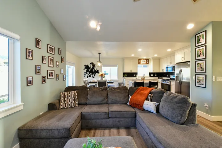 Wood-finish flooring throughout, an open-concept layout, recessed lighting, and a kitchen featuring white cabinetry and stainless steel appliances